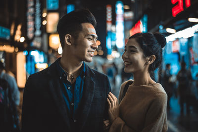 Smiling couple standing on street in city at night