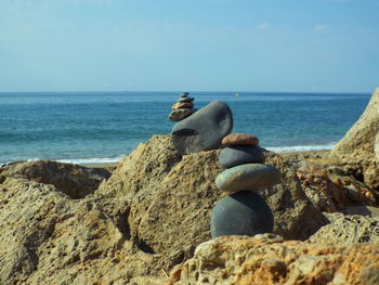 Stacked stones at beach against sky