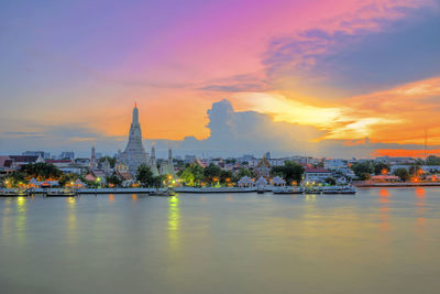 River in city against sky during sunset