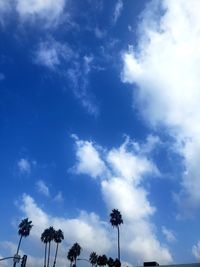 Low angle view of silhouette palm trees against blue sky