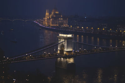 Illuminated chain bridge over river at night