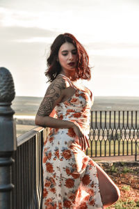 Portrait of young woman standing against railing