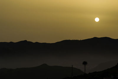 Scenic view of silhouette mountains against orange sky