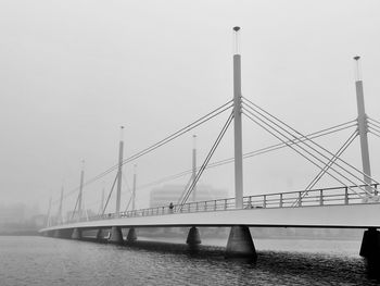 Bridge over calm river against clear sky