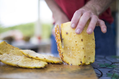 Detailed view of man slicing fresh pineapple outdoors