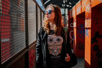 Portrait of young woman standing against wall