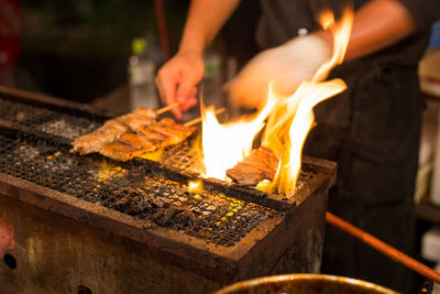 Close-up of man preparing food on barbecue grill