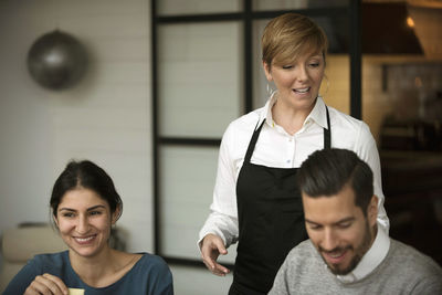 Happy business people and woman wearing apron while winetasting