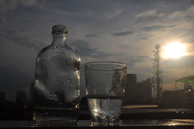 Glass of water bottle against sky