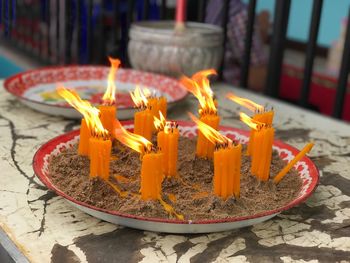 Close-up of burning candles in plate at temple