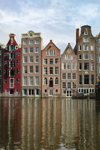Buildings by river against sky