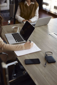 Woman taking notes during business meeting