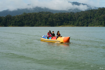 People in boat on water against sky