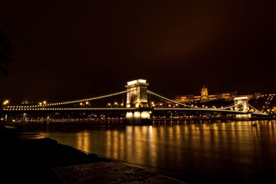 Illuminated bridge over river at night