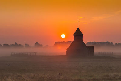 Church on field against orange sky