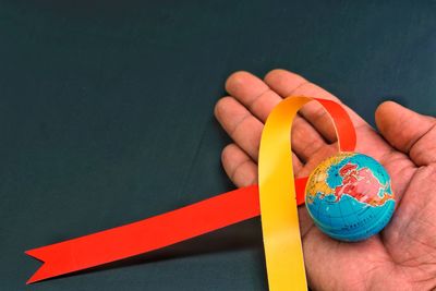 Cropped hand holding globe and ribbon