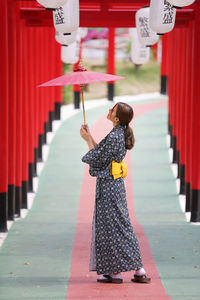 Woman holding umbrella standing outdoors in temple