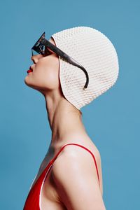 Young woman wearing hat against blue background