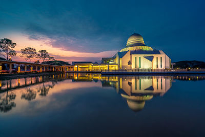 Reflection of illuminated building in lake at sunset