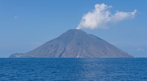 Scenic view of sea and mountains against blue sky