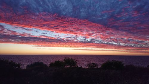 Scenic view of sea against dramatic sky during sunset