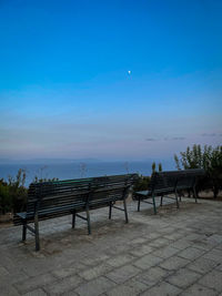 Empty bench on table against blue sky