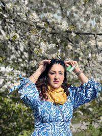 Portrait of young woman standing against trees