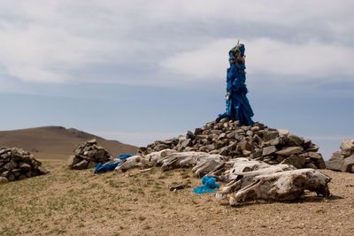 Stack of logs on mountain against sky