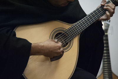 Midsection of man playing acoustic guitar