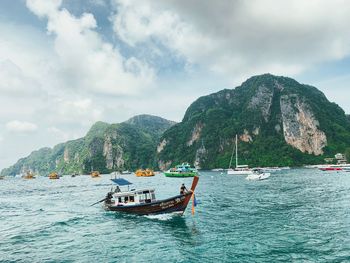 Boats in sea against mountain range