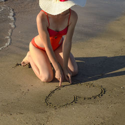 Low section of woman wearing hat on beach
