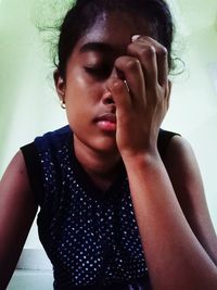 Close-up portrait of young woman against wall at home