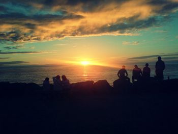 Silhouette people on beach at sunset