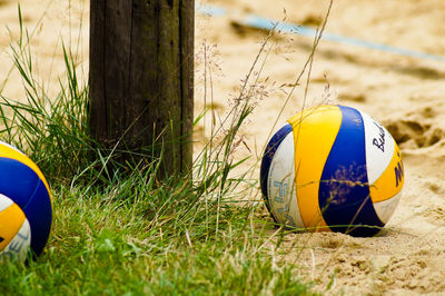 Close-up of volleyballs by wooden post at beach