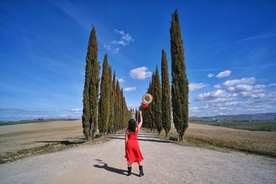 Woman with umbrella standing on road against sky