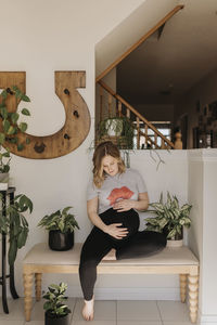 Woman sitting on potted plant at home