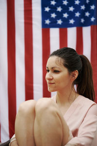 A young girl sitting with the american flag in the background. concept of america