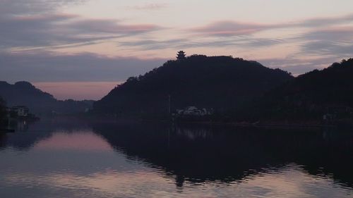 Silhouette trees by lake against sky during sunset