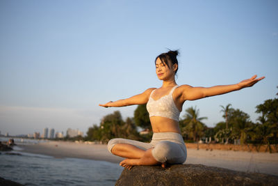 Full length of woman sitting on beach against clear sky