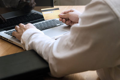 Midsection of man using laptop on table