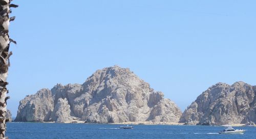 View of calm blue sea against rocky mountains