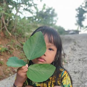 Portrait of cute girl holding leaves