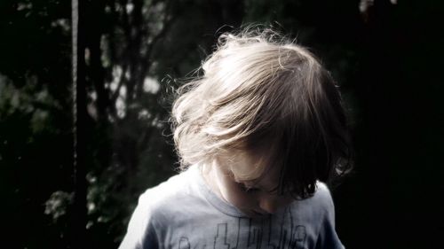 Close-up of boy against trees on sunny day