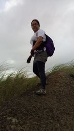 Full length of man with arms raised against sky