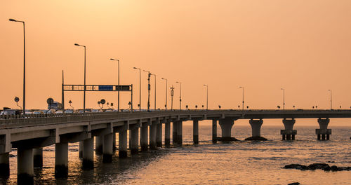 Bridge over river against sky during sunset