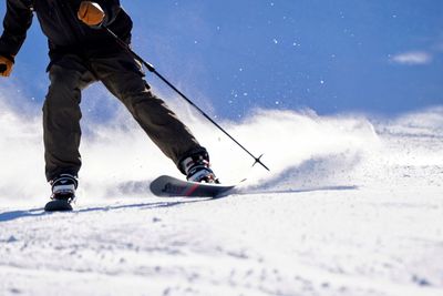 Low section of man skiing on snow covered field