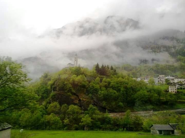 tree, mountain, sky, building exterior, scenics, green color, tranquil scene, beauty in nature, landscape, weather, cloud - sky, built structure, tranquility, architecture, nature, house, cloudy, overcast, idyllic, lush foliage