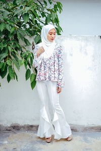 Young woman in headscarf looking away against wall