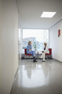 Female doctors sitting in hospital and talking to each other