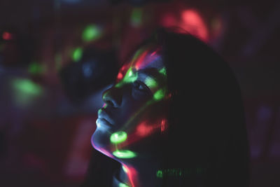 Close-up of thoughtful young woman in illuminated room at night